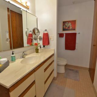 A neatly organized bathroom with red accents and a large mirror.
