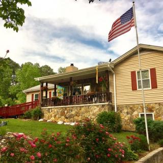 A quaint house with a patio, surrounded by a well-maintained garden and an American flag waving in the breeze.