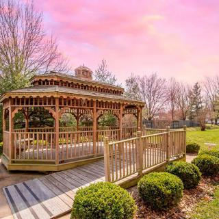 A charming wooden gazebo set in a picturesque park with a vibrant sunset sky.