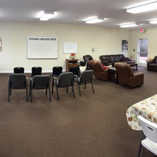 A community meeting room featuring rows of chairs, a whiteboard, and comfortable sofas.