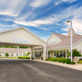 A welcoming entrance of a building with a covered driveway under a partly cloudy sky.