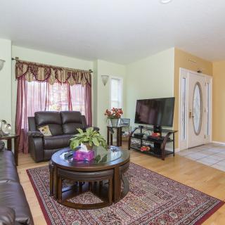 A cozy living room featuring leather sofas, a wooden coffee table, and a television set, accented with a patterned rug and elegant curtains.