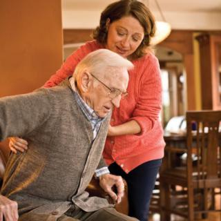 A caregiver assisting an elderly person indoors.
