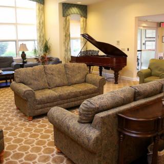 A cozy living room featuring a grand piano and comfortable sofas.