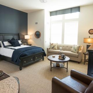 A modern bedroom with elegant furniture, featuring a bed, sofa, and table lamps.