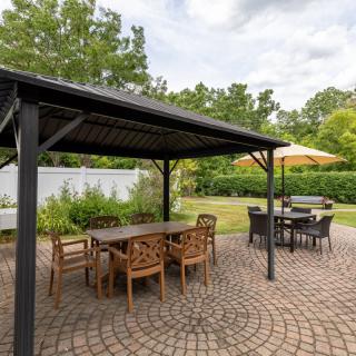A beautiful patio with a gazebo and outdoor seating, set in a lush garden.