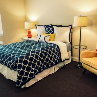 A cozy bedroom with a stylish bed, vibrant lamps, and comfortable seating.