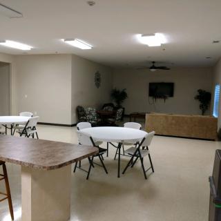 A spacious indoor meeting room with tables, chairs, and a television.