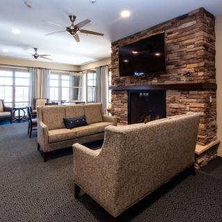 A modern living room featuring a stone fireplace, a mounted television, and comfortable sofas.