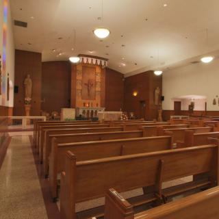 An interior view of a church showing rows of wooden pews facing the altar.