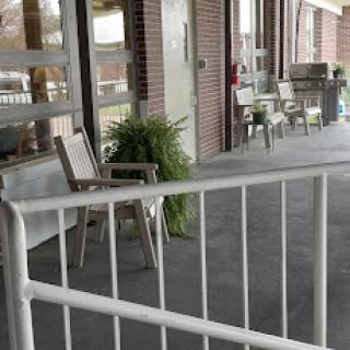 A cozy outdoor seating area with chairs and plants, providing a welcoming space outside a building.