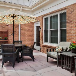 A cozy patio with outdoor furniture and a large umbrella against a brick wall.