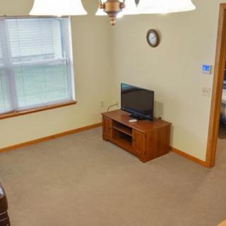 A simple living room with a television, clock, and large window.