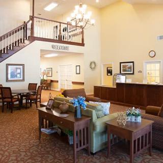 A welcoming hotel lobby featuring comfortable seating, a staircase, and a reception desk.