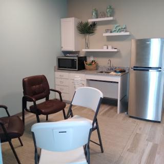 A cozy, well-lit room featuring a small kitchenette with seating arrangements.