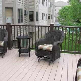 An outdoor patio with wicker chairs and a small table on a residential deck.