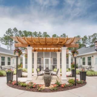 A beautifully designed courtyard with a central pergola surrounded by greenery.