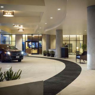 A luxurious hotel entrance at night with a parked car in the driveway.