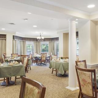 A spacious and elegantly decorated dining room with multiple tables set for guests.