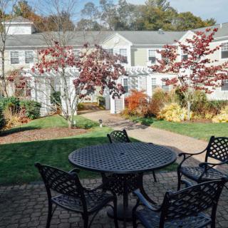 A serene patio area with outdoor furniture surrounded by a garden in autumn.