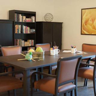 A conference room with a meeting table surrounded by chairs, bookshelves in the background, and decorative items.