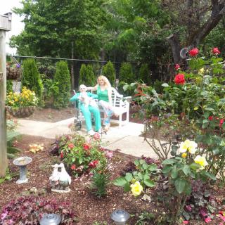 Two people sitting on a bench in a colorful garden surrounded by various flowers.