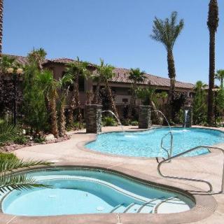 A scenic view of an outdoor swimming pool surrounded by palm trees and a spa area, evoking a tropical resort atmosphere.