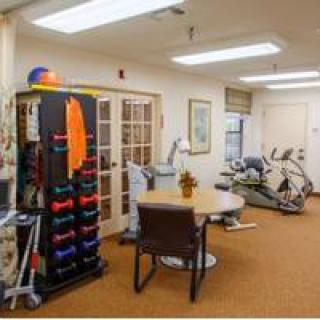 A rehabilitation therapy room equipped with exercise machines and dumbbells.