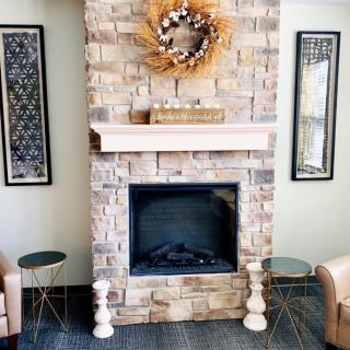 A cozy living room featuring a brick fireplace adorned with a wreath, flanked by two decorative mirrors and side tables.