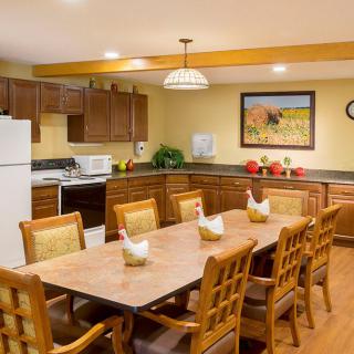 A cozy kitchen and dining area with wooden cabinets, a large table, and modern appliances.