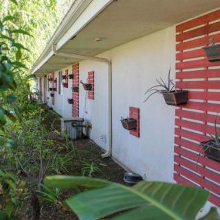 An exterior view of a building with hanging planters and lush greenery along the side.