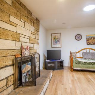 A cozy living area featuring a stone wall with a fireplace, a television on a stand, and a bed with decorative artwork on the walls.