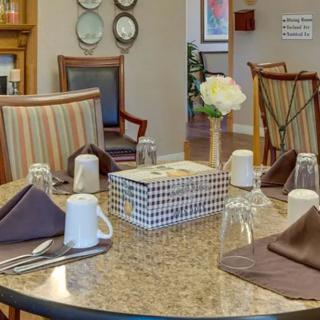 A neatly arranged dining table with napkins, glasses, and a flower vase.
