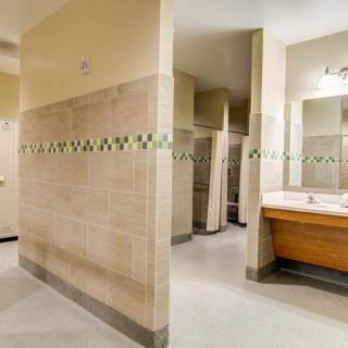 A clean public restroom with tiled walls, sinks, mirrors, and stalls.