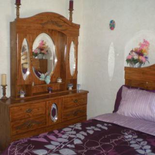 A cozy bedroom with a wooden dresser and mirror alongside a bed with purple bedding.