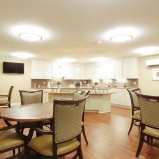 A well-lit dining area with multiple tables and chairs adjacent to a spacious kitchen.