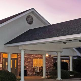 A brick building with white columns and a covered entrance at dusk.