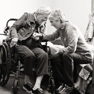 A caregiver tenderly assists an elderly woman in a wheelchair, highlighting the compassion in elder care.