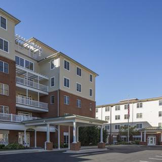 A modern multi-story apartment building under a clear blue sky.