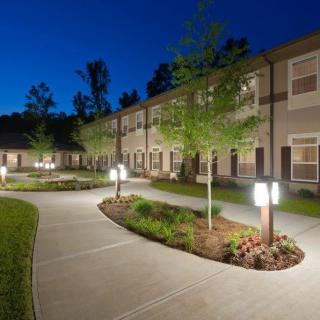 A well-lit residential building with a landscaped pathway at night.
