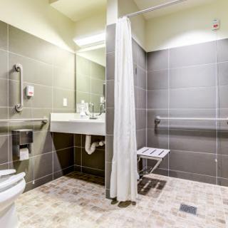 An accessible bathroom featuring a shower, sink, and safety amenities for ease of use.
