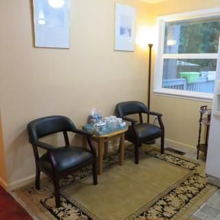 A cozy waiting room with two chairs and a small table under soft lighting.