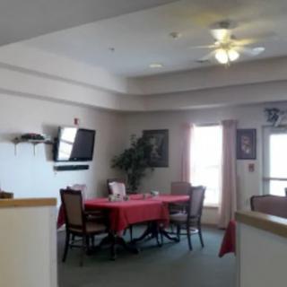 A dining area with a table and chairs, featuring a wall-mounted television and a ceiling fan.