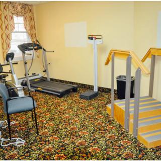 A small indoor exercise room featuring a treadmill, stationary bike, and scale on a carpeted floor.