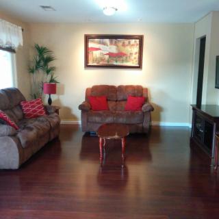 A cozy living room with brown sofas, a small wooden table, vibrant decor, and a framed artwork on the wall.