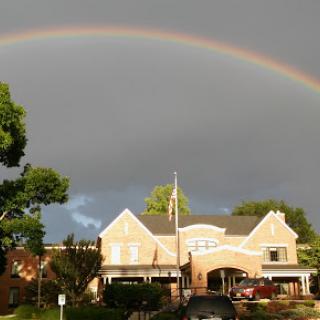A vibrant rainbow stretches across a gray sky above a charming building.