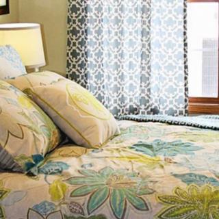 A cozy bedroom featuring a bed with floral-patterned bedding, accented by matching pillows and decorative curtains.