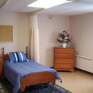 A simple, minimalist bedroom with a single bed and a dresser.