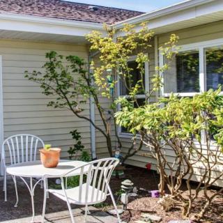 A sunlit patio with white metal furniture and surrounding greenery.