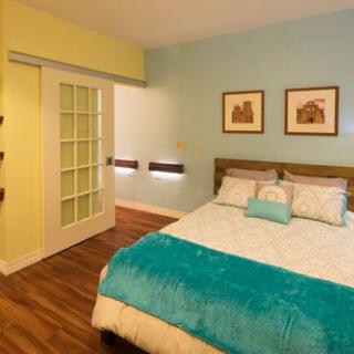 A modern and cozy bedroom with a double bed, colorful decor, and wooden flooring.